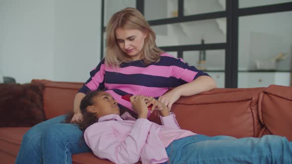 Lovely Mother and Daughter Relaxing on Sofa Indoor