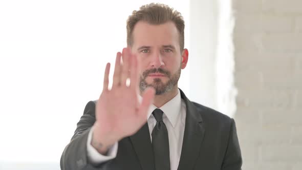 Middle Aged Businessman Showing Stop Sign By Hand