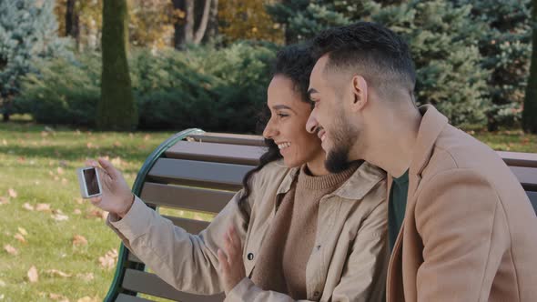 Positive Hispanic Couple Making Video Call Use Phone Man and Woman Smiling Happily Waving Hello Girl