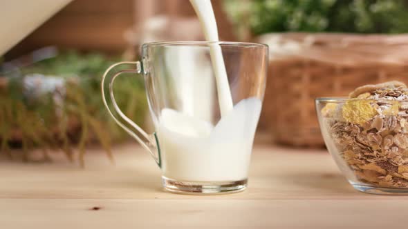 Pouring Fresh Natural Farm Organic Milk to Glassware on Wooden Table Serving By Muesli Granola