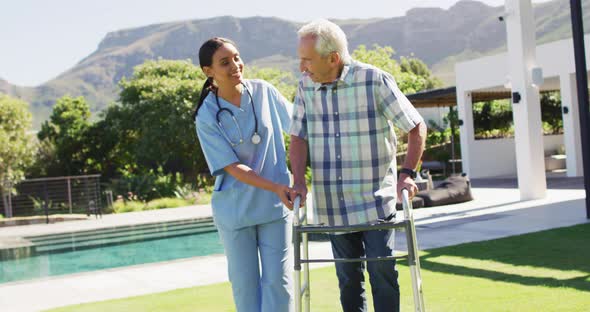 Video of happy biracial female doctor taking care of caucasian senior man in rest home garden