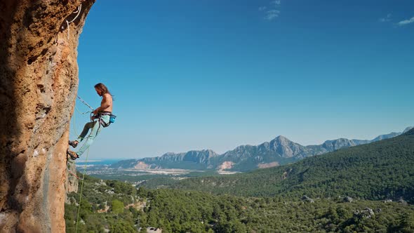 Side View of Strong Attractive Man Rock Climber Getting Ready to Descend From Vertical Cliff on Top