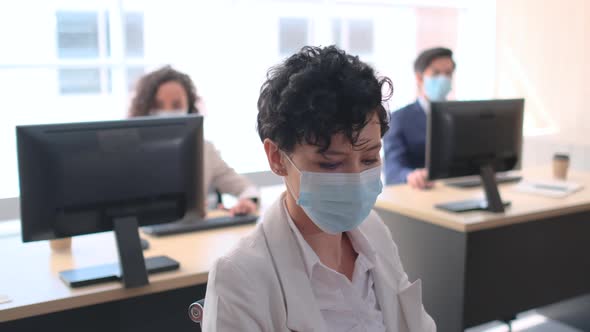 Group of business workers with hygiene mask work with computer in the office with day light