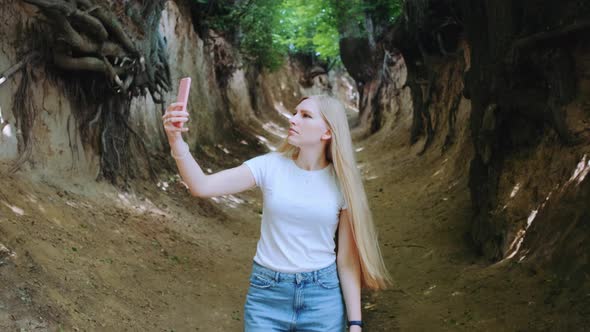 Blonde Young Woman Making Photos on Smartphone in Magical Roots Gorge