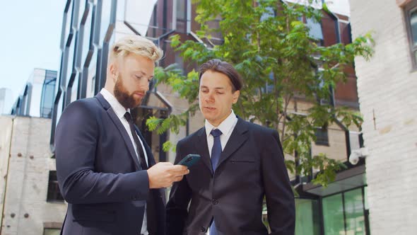 Confident businessman and his colleague in front of modern office building.