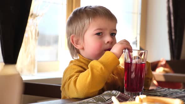 Child Boy with Blonde Hair Baby Drinking Lemonade in Cafe