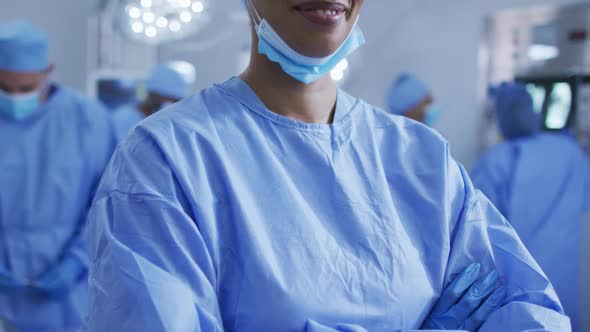 Portrait of mixed race female doctor standing in operating theatre smiling to camera