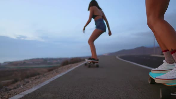 Close - Up of a Skateboard and Two Girls Who Are Riding on Boards From a Mountain on a Background of