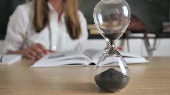 Pouring Sand in an Hourglass Standing on the Desk in Workspace