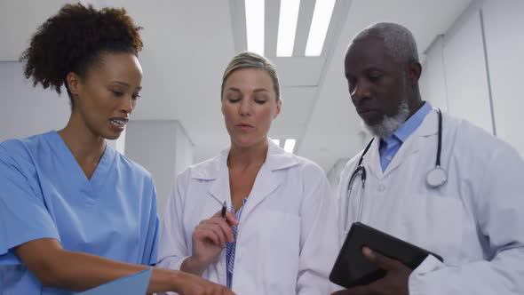 Diverse doctors and medical workers standing in hospital corridor and talking