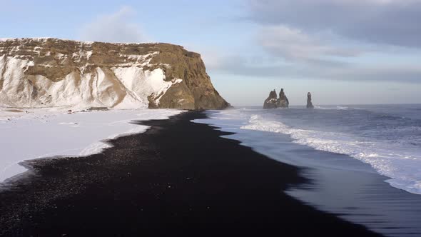 Flight Over the Black Sand Beach of Southern Iceland Covered in Snow