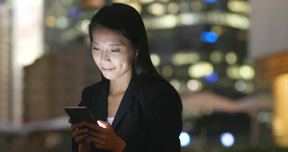 Businesswoman working on cellphone at night 