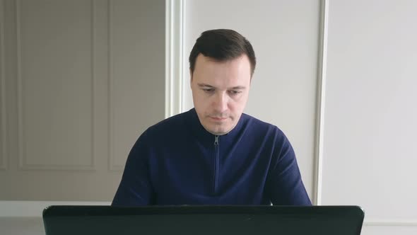 Young male worker freelancer using computer laptop sitting at home office desk