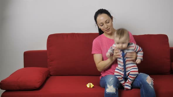 Baby Boy Learning To Jump on Sofa with Mother