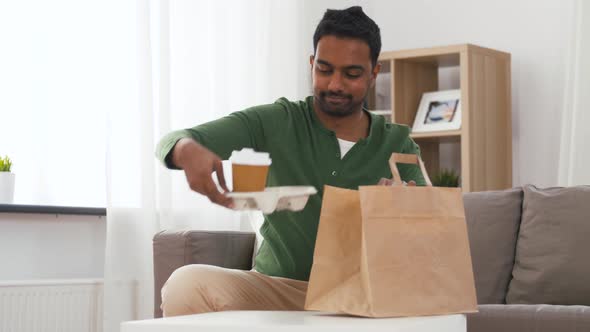 Indian Man with Takeaway Coffee and Food at Home