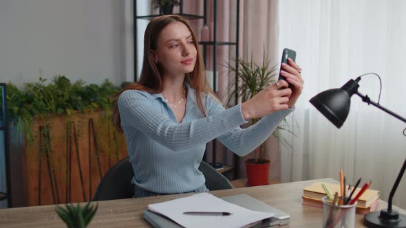 Young Woman Blogger Taking Selfie Portraits on Smartphone for Social Media Vlog While Working Home