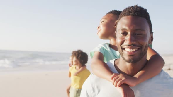 Smiling african american family embracing and walking on sunny beach