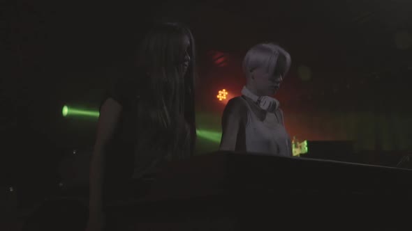 Two Beautiful Young Women DJ Play the Music on the Mixing Console in the Nightclub