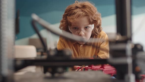 Red-haired Boy Watching Machine Working in Classroom