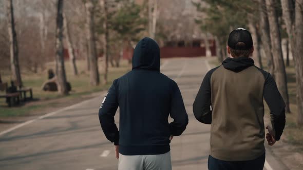 Rear View Two Adult Men Jogging on Park Road Outside in City. Physical Training for Cardio Endurance