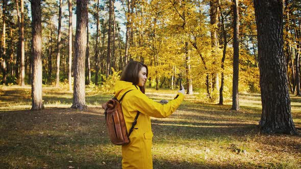 Young Female Smiling Taking Photos of Environment on Her Cellphone During Walk in Autumn Forest