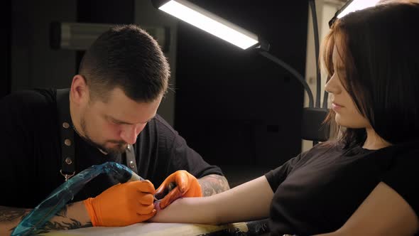 Tattoo Artist Makes a Tattoo Woman on a Arm, Works in Studio. Slow Motion Close Up View