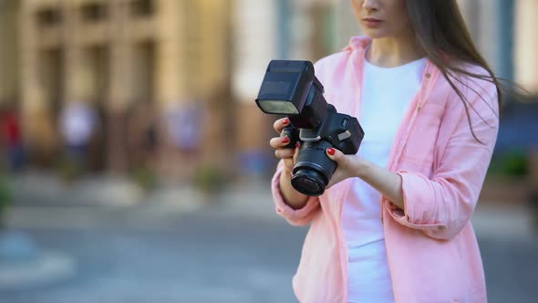 Female Photographer Adjusting Camera Exposure Before Photo Shoot on City Street