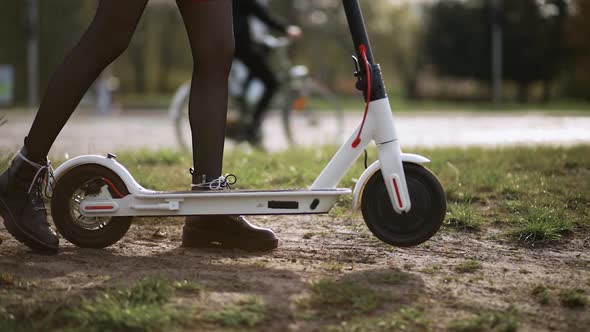 Woman Spins Electric Scooter's Front Wheel on Sand in Place