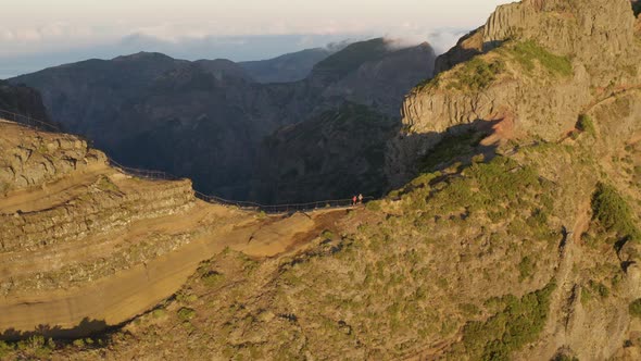 Aerial of 2 Hikers walking on a small path close to Pico do Arieriro early morning, Madeira