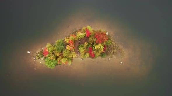 Top Down Aerial View Above Scenic Small Island with Fall Trees in Cinematic Lake