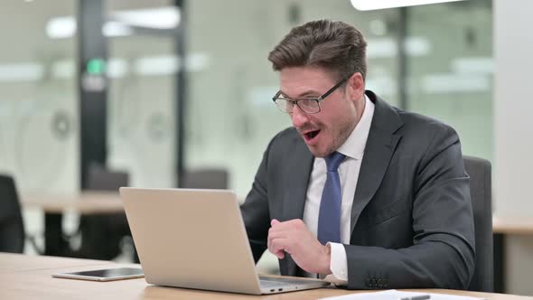 Excited Middle Aged Businessman Celebrating Success on Laptop in Office
