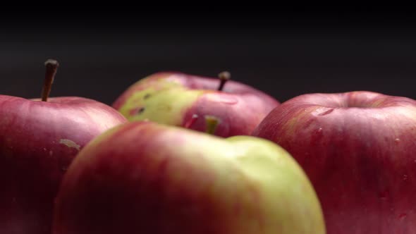 Fresh sweet red apples are spinning on a plate on a black background.