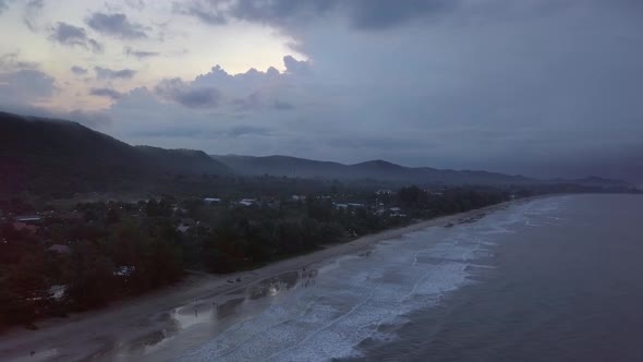 An aerial view of a dramatic landscape of an island during sunrise. The camera is slowly moving back