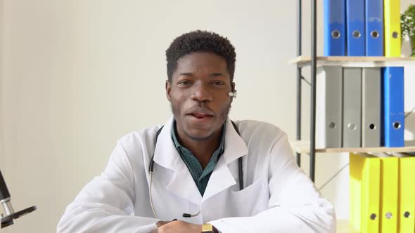 Young African American Male Doctor Having Chat or Consultation on Laptop Looking Directly to the