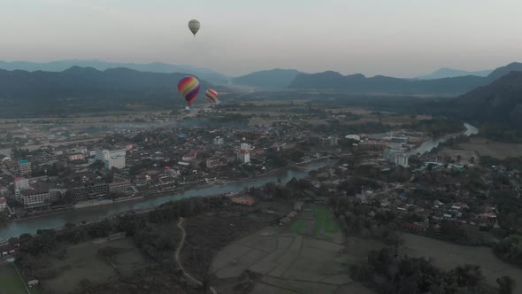 Aerial: Vang Vieng backpacker travel destination in Laos, Asia. Hot air balloons