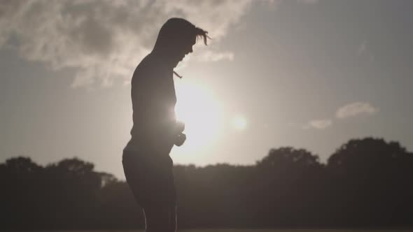 Man In Park Skipping Rope To Keep Fit With The Dying Sun Behind Him In Slow Motion - Ungraded