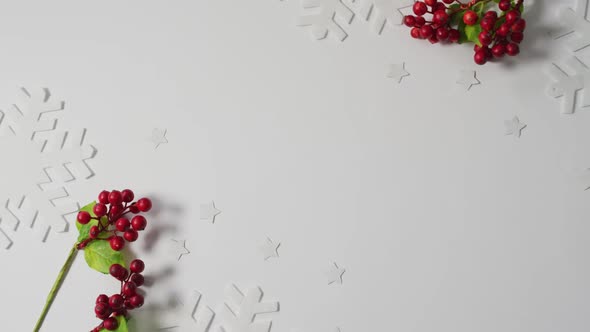 Video of christmas sprigs with red berries, snowflake patterns and copy space on white background