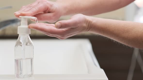 Woman applies cleansing hygiene remedy to her hands to kill infectious bacteria