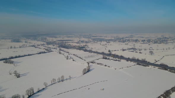 View of snowy fields from hill with drone