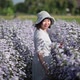 Asian woman walking in a flower garden and looking back at the camera, slow motion. - VideoHive Item for Sale