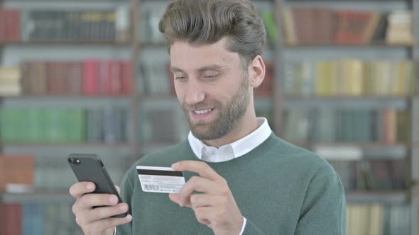 Young Man Using Credit Card on His Cellphone