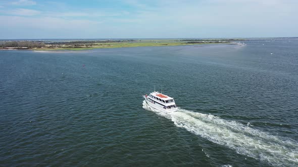 An aerial drone view over Jones Inlet on a sunny day. The camera dolly in towards a tour boat. It th