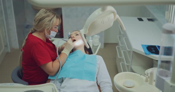 Beautiful Woman Dentist Working Treating a Tooth to a Patient