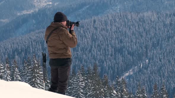 Hiker Photographer Taking Pictures of Snowy Nature in Winter Mountains