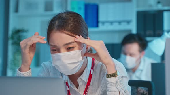 Asian young business woman wear mask, feel headache from work in office.