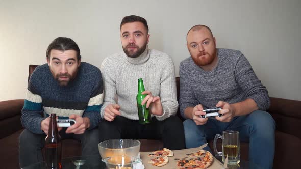 Image of Three Happy Bearded Men Playing Videogame with Wireless Controllers Together