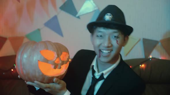 A Guy in a Creepy Costume with a Jacko'lantern Poses in Front of the Camera on Halloween