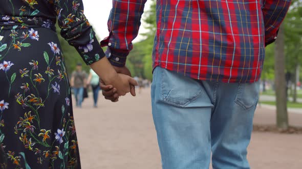 Close-up of Diverse Female and Male Holding Hands Walking in City Park