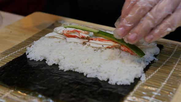 the Hands of the Sushi Chef Spin a Roll of Rice Squid Meat Cucumber and