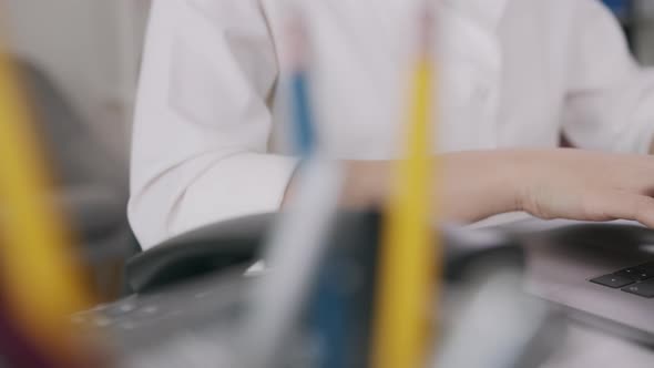 close-up of woman hands typing on laptop keyboard on the table.